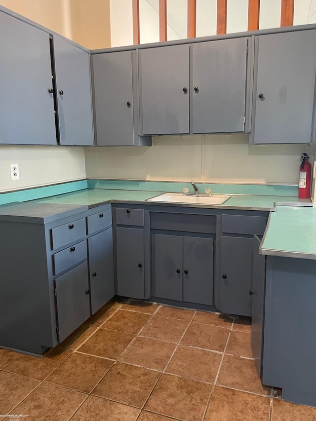 kitchen with a sink, gray cabinets, and light countertops
