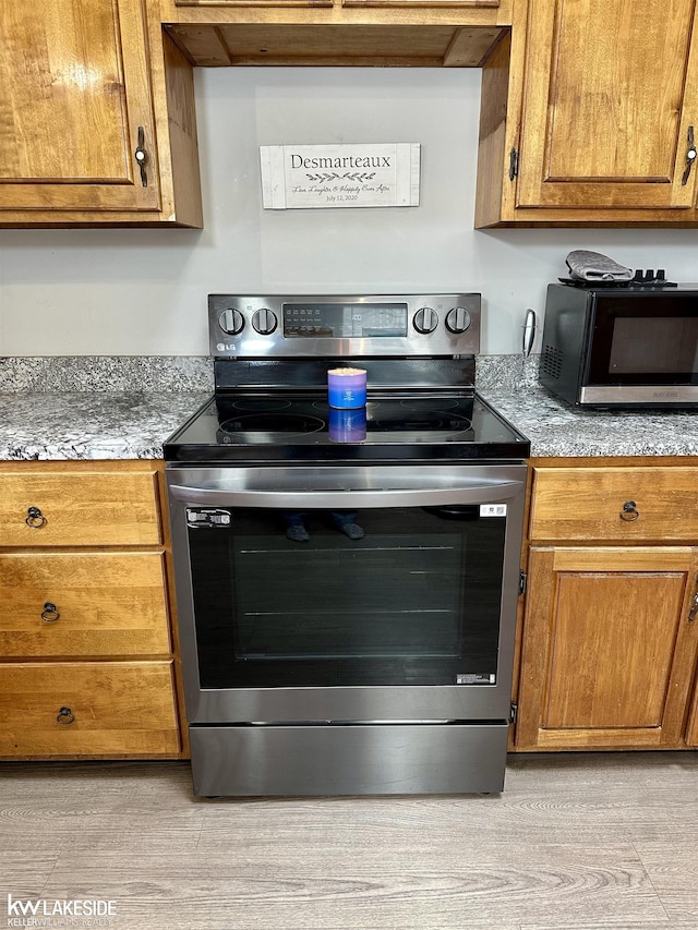 9602 Cornell Ave, Clarkston, MI 48348 - kitchen with stainless steel electric range, black microwave, and brown cabinets