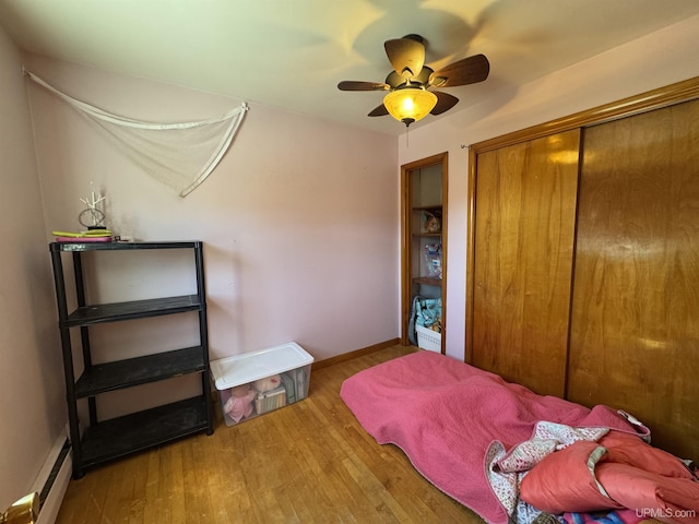 643 S Pine St, Ishpeming, MI 49849 - bedroom featuring baseboard heating, wood finished floors, a closet, ceiling fan, and baseboards