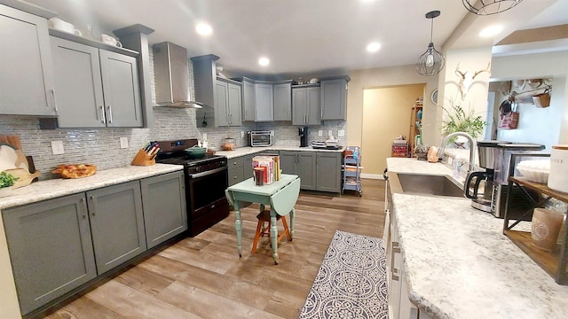 3787 Shepherd Rd, Midland, MI 48880 - kitchen with stainless steel gas range, a sink, wall chimney range hood, gray cabinets, and tasteful backsplash