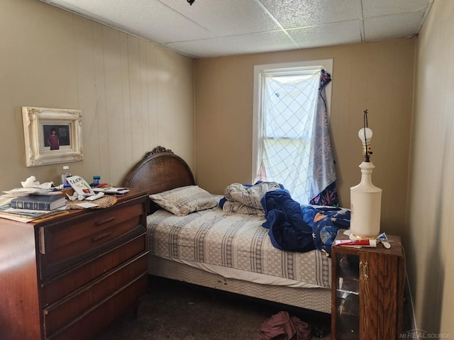 bedroom with dark colored carpet and a drop ceiling