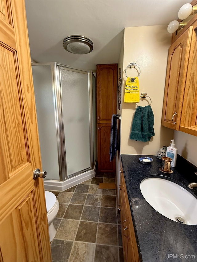 full bath with a shower stall, vanity, toilet, and stone finish floors
