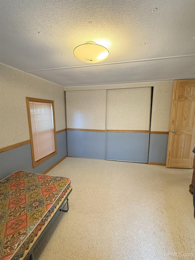 unfurnished bedroom featuring a textured ceiling, carpet flooring, and a closet