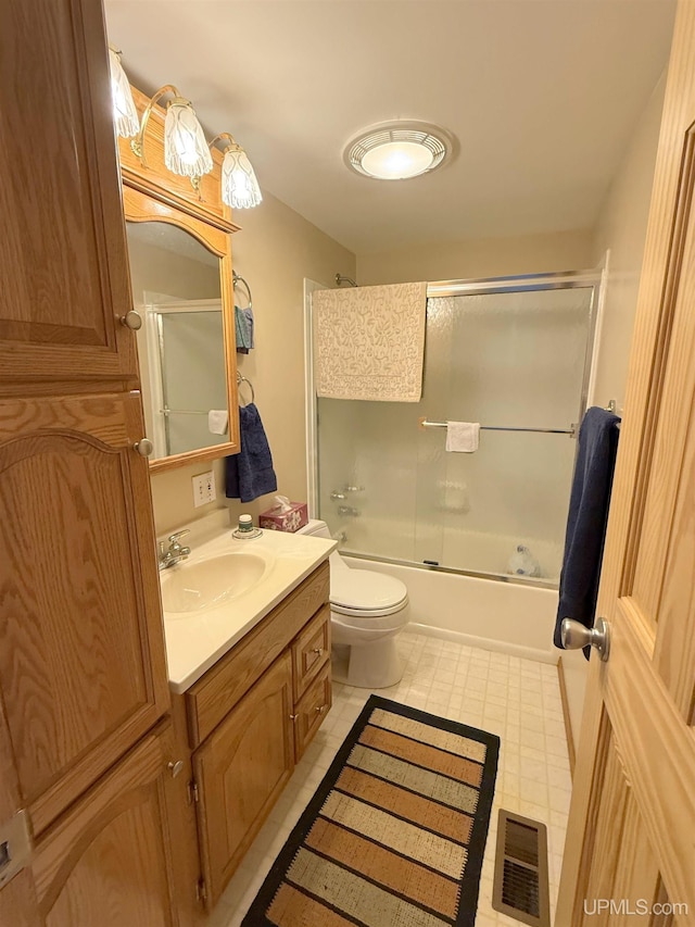 bathroom with vanity, toilet, and bath / shower combo with glass door