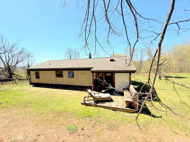 rear view of property featuring a yard, roof with shingles, and a wooden deck