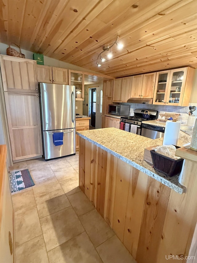 kitchen with stainless steel appliances, light brown cabinetry, a peninsula, light tile patterned floors, and vaulted ceiling