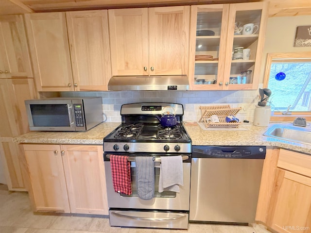 kitchen featuring appliances with stainless steel finishes, under cabinet range hood, light brown cabinetry, and tasteful backsplash