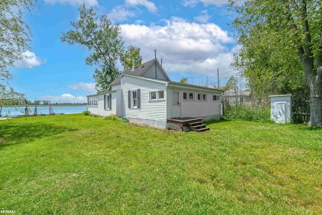 back of house with a lawn and a deck with water view