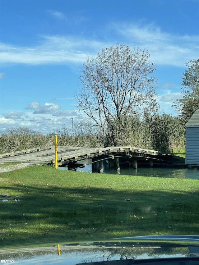 view of community featuring a water view, a lawn, and a boat dock