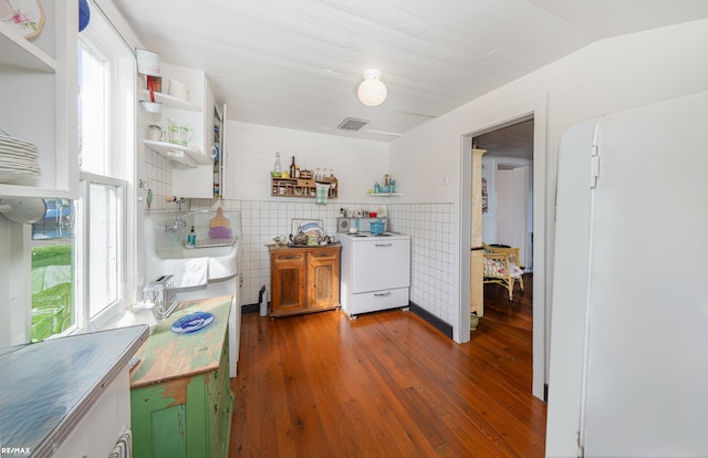 kitchen with open shelves, stove, tile walls, healthy amount of natural light, and wood finished floors