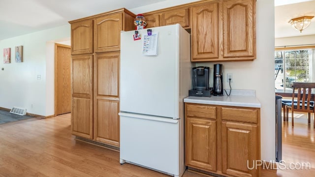 1000 N Evergreen Dr, Iron Mountain, MI 49801 - kitchen with freestanding refrigerator, light wood finished floors, light countertops, and brown cabinets