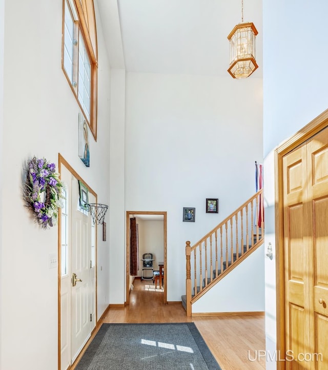 1000 N Evergreen Dr, Iron Mountain, MI 49801 - entryway with a high ceiling, stairway, wood finished floors, a chandelier, and baseboards
