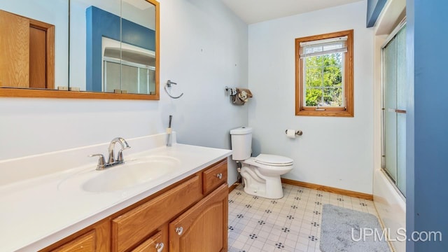 1000 N Evergreen Dr, Iron Mountain, MI 49801 - bathroom with toilet, baseboards, vanity, and combined bath / shower with glass door