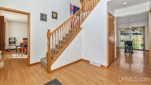 1000 N Evergreen Dr, Iron Mountain, MI 49801 - stairs featuring wood finished floors, baseboards, and a chandelier
