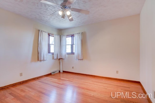 8962 Stagecoach Q.5 Ave, Gladstone, MI 49837 - empty room featuring light wood-style flooring, a ceiling fan, baseboards, and a textured ceiling