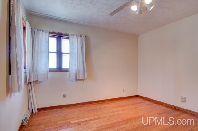 8962 Stagecoach Q.5 Ave, Gladstone, MI 49837 - spare room featuring light wood-type flooring, ceiling fan, baseboards, and a textured ceiling