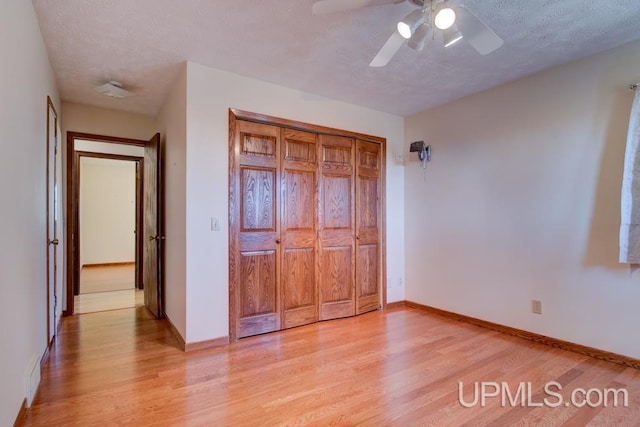 8962 Stagecoach Q.5 Ave, Gladstone, MI 49837 - unfurnished bedroom featuring light wood-type flooring, baseboards, ceiling fan, and a textured ceiling