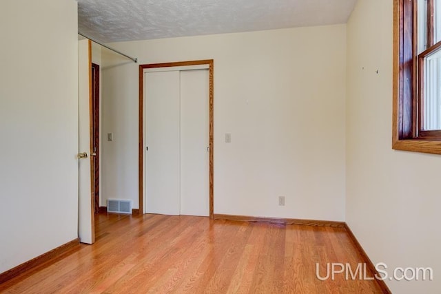 8962 Stagecoach Q.5 Ave, Gladstone, MI 49837 - unfurnished bedroom with light wood-type flooring, baseboards, a closet, and a textured ceiling