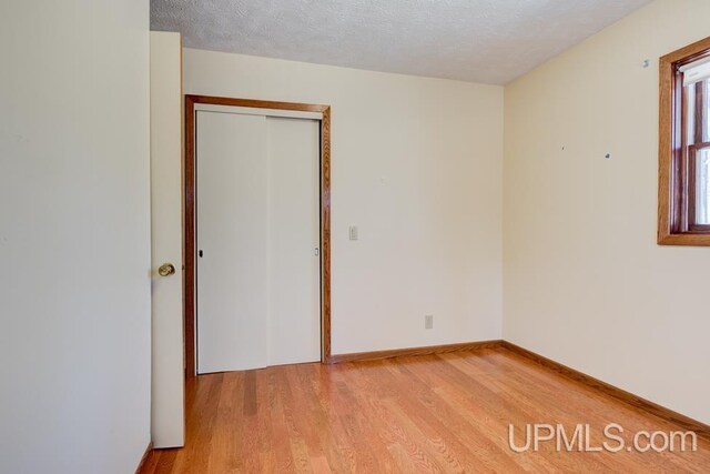 8962 Stagecoach Q.5 Ave, Gladstone, MI 49837 - spare room featuring light wood-style floors, a textured ceiling, and baseboards