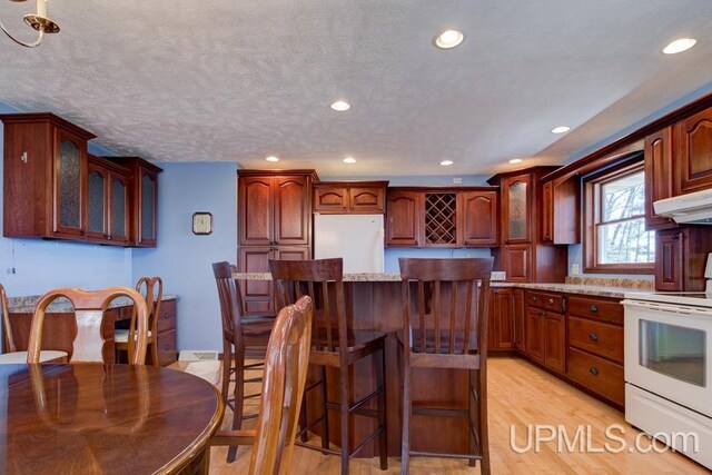 8962 Stagecoach Q.5 Ave, Gladstone, MI 49837 - kitchen with white appliances, glass insert cabinets, a kitchen island, recessed lighting, and a kitchen bar