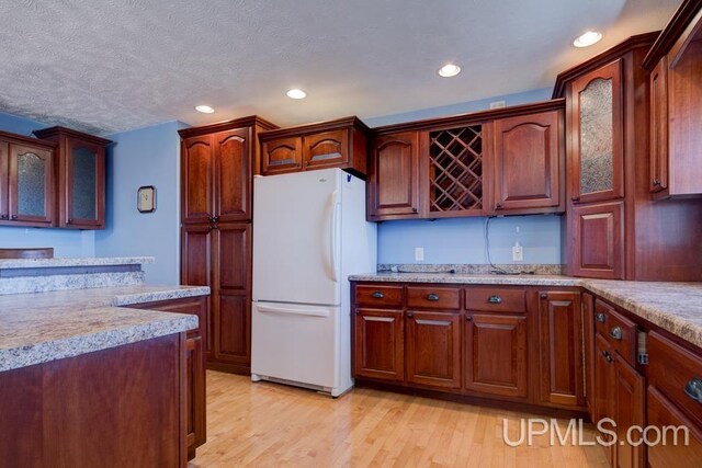 8962 Stagecoach Q.5 Ave, Gladstone, MI 49837 - kitchen featuring freestanding refrigerator, light countertops, light wood-style flooring, recessed lighting, and glass insert cabinets