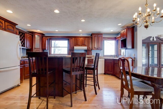 8962 Stagecoach Q.5 Ave, Gladstone, MI 49837 - kitchen with freestanding refrigerator, light wood finished floors, a textured ceiling, a chandelier, and a center island