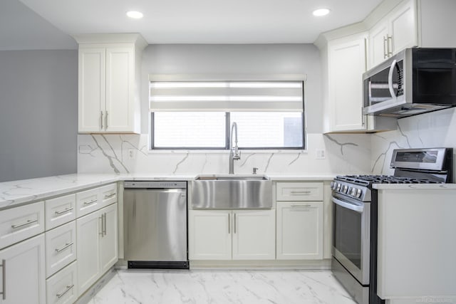 kitchen with appliances with stainless steel finishes, a sink, white cabinetry, light stone counters, and recessed lighting