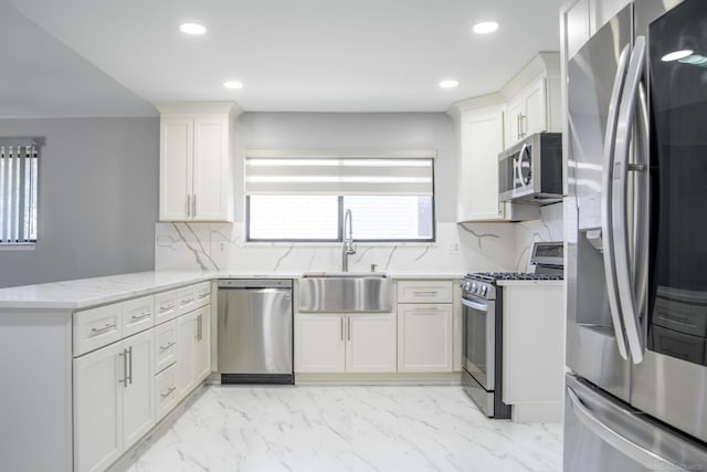kitchen with stainless steel appliances, a sink, a peninsula, decorative backsplash, and light stone countertops