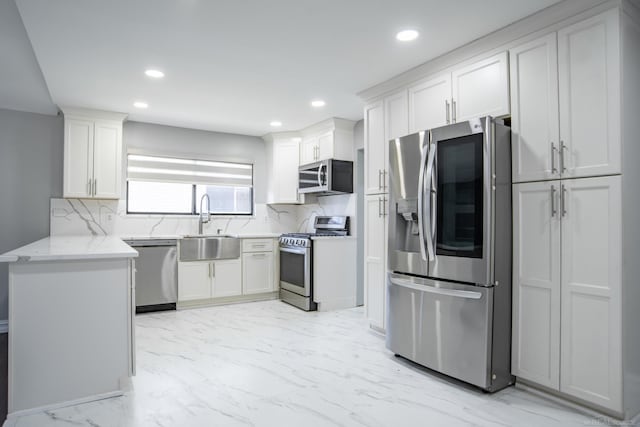 kitchen with appliances with stainless steel finishes, a sink, decorative backsplash, recessed lighting, and light stone countertops