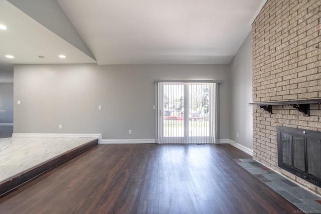 unfurnished living room with lofted ceiling, dark wood finished floors, a fireplace, baseboards, and recessed lighting