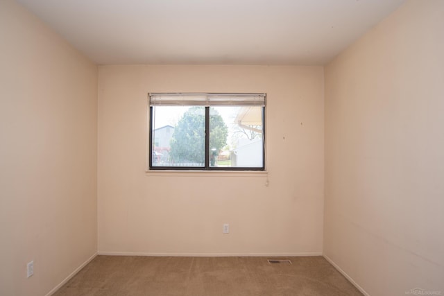 unfurnished room with light carpet and baseboards