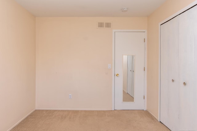 unfurnished bedroom featuring light carpet, a closet, and baseboards