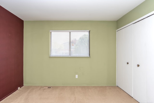 unfurnished bedroom featuring a closet, light carpet, and baseboards