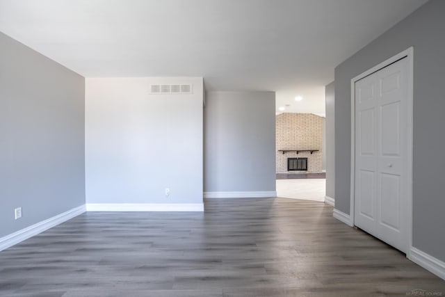 unfurnished living room with wood finished floors, baseboards, and a fireplace