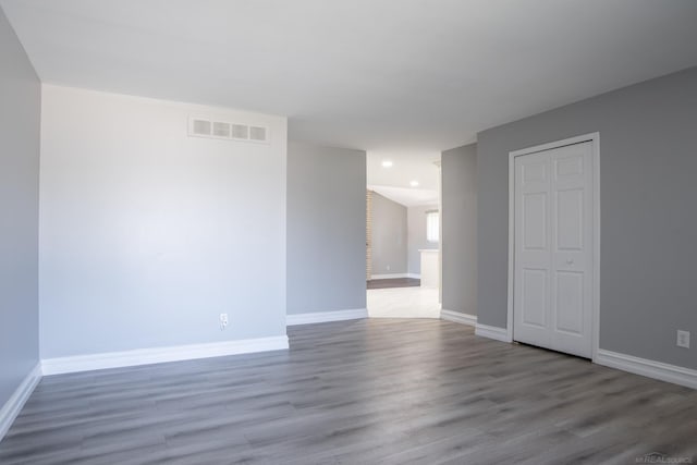 empty room featuring baseboards, wood finished floors, and recessed lighting