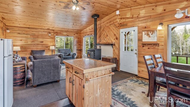 9190 Blue Jay Ln, Florence T-Wi, WI 54121 - kitchen featuring lofted ceiling, dark carpet, wood walls, a wood stove, and a ceiling fan