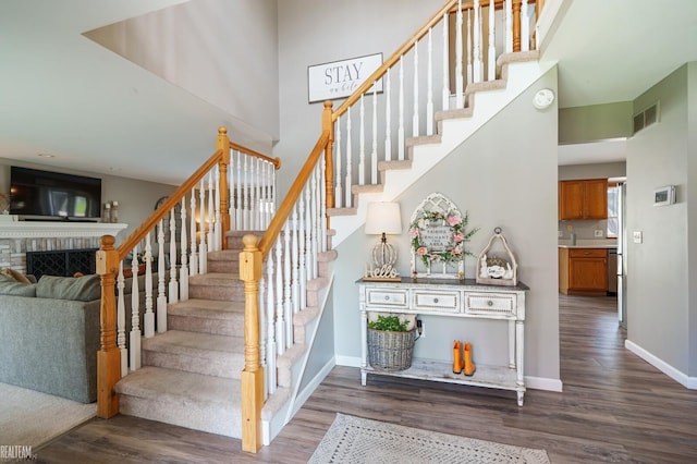 35657 Pierce St, Richmond, MI 48062 - stairway featuring wood finished floors, baseboards, a fireplace, and a towering ceiling