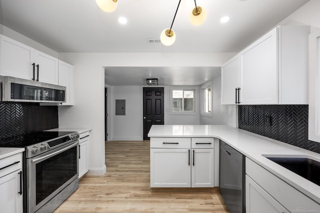 kitchen with appliances with stainless steel finishes, a peninsula, light countertops, tasteful backsplash, and recessed lighting