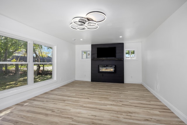 unfurnished living room with a fireplace, a chandelier, baseboards, light wood-type flooring, and recessed lighting