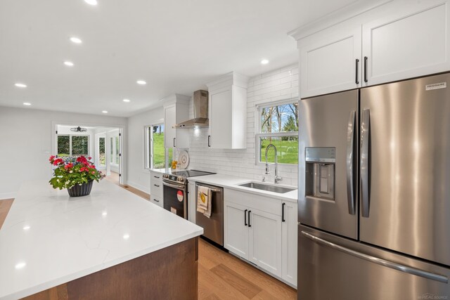 7533 Roberta Ln, Washington T-Wi, MI 48094 - kitchen featuring stainless steel appliances, a sink, wall chimney exhaust hood, light wood finished floors, and white cabinetry
