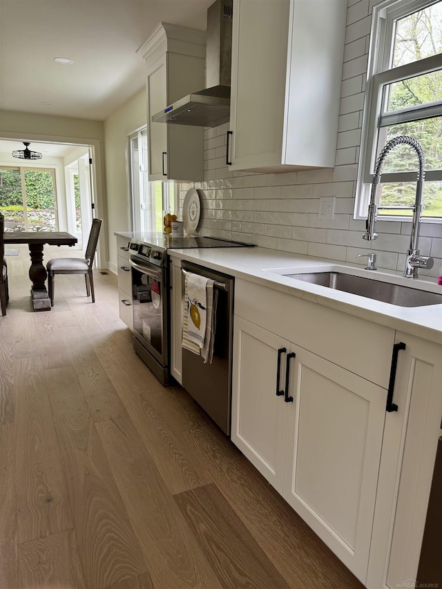 7533 Roberta Ln, Washington T-Wi, MI 48094 - kitchen with wall chimney range hood, a sink, wood finished floors, appliances with stainless steel finishes, and light countertops