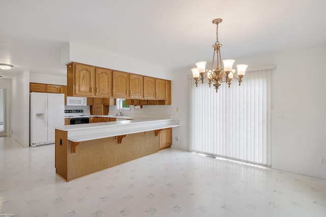 kitchen with white appliances, light flooring, a peninsula, and brown cabinetry