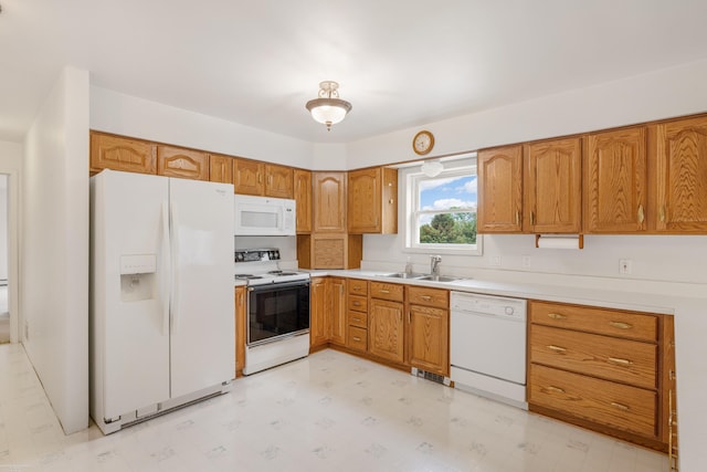 kitchen featuring white appliances, a sink, and brown cabinetry