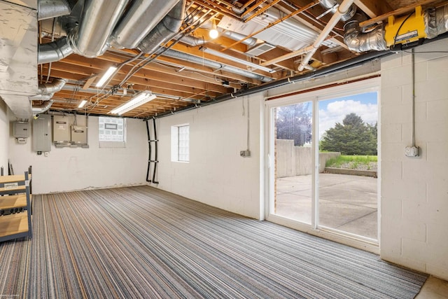 below grade area with concrete block wall, healthy amount of natural light, electric panel, and carpet
