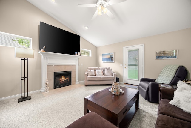 living area with ceiling fan, light carpet, a tile fireplace, vaulted ceiling, and healthy amount of natural light