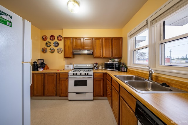405 Mustang St, Gwinn, MI 49841 - kitchen with white appliances, under cabinet range hood, brown cabinets, and a sink