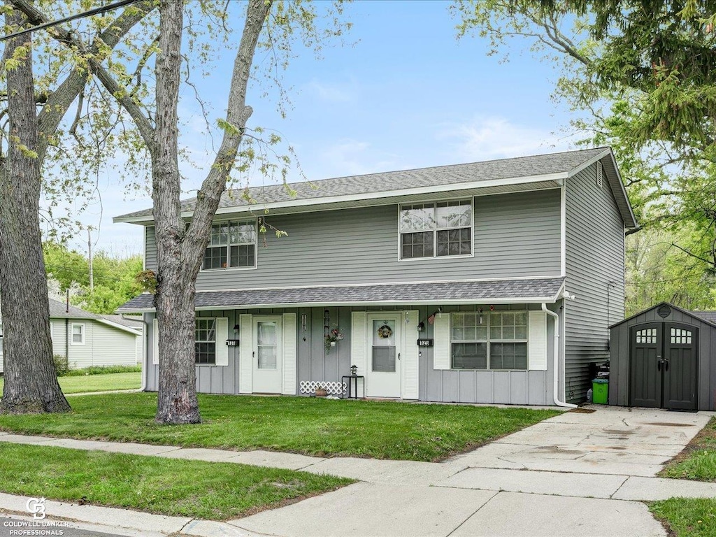 129/131 Taylor St, Port Huron, MI 48060 - view of front of house featuring a storage unit, board and batten siding, an outdoor structure, a front yard, and concrete driveway