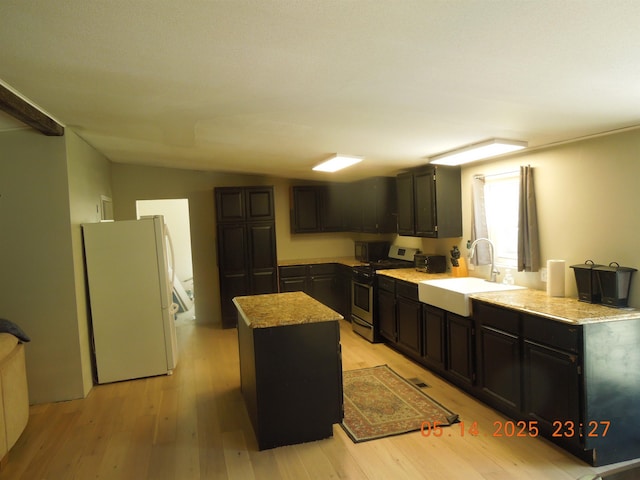 1582 Oakwood St, Gladwin, MI 48624 - kitchen featuring freestanding refrigerator, gas range, a sink, a center island, and light wood finished floors