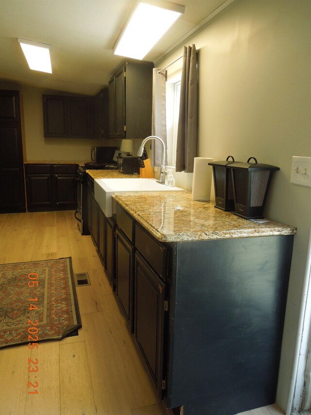 1582 Oakwood St, Gladwin, MI 48624 - kitchen featuring light wood-style flooring, stainless steel electric range, a sink, and light stone counters