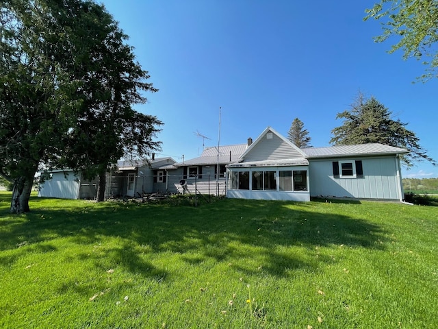 rear view of property with a yard, a sunroom, and metal roof